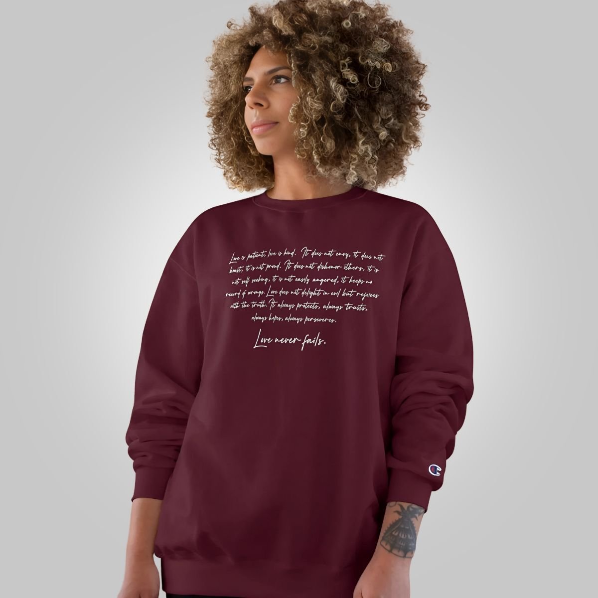Black Inkblot Champion unisex sweatshirt with "Love Never Fails" graphic, comfortable casual wear for AU, NZ, and US sizes.